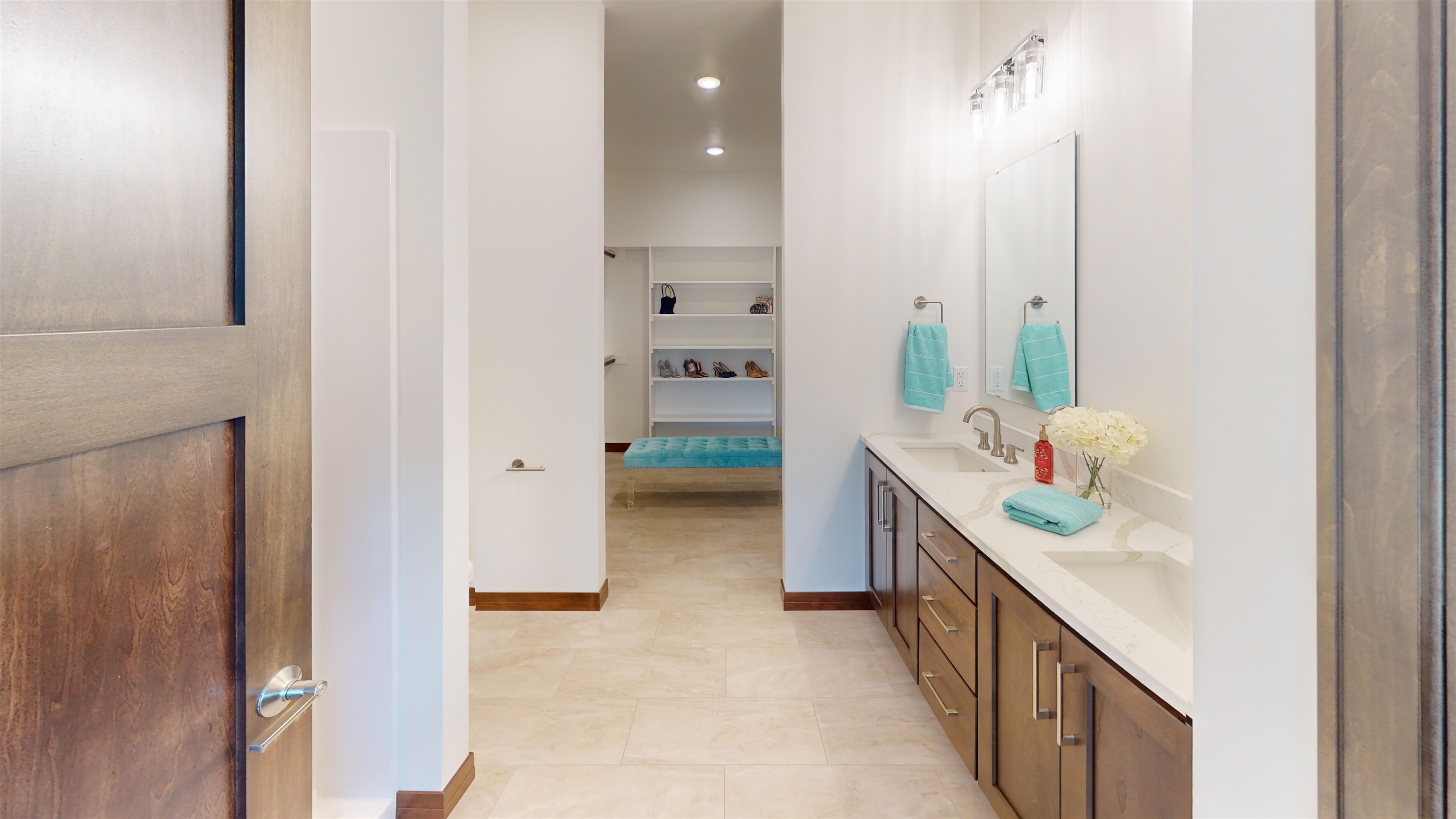 Large master bath with large walk in shower and dual sinks leading to large closet